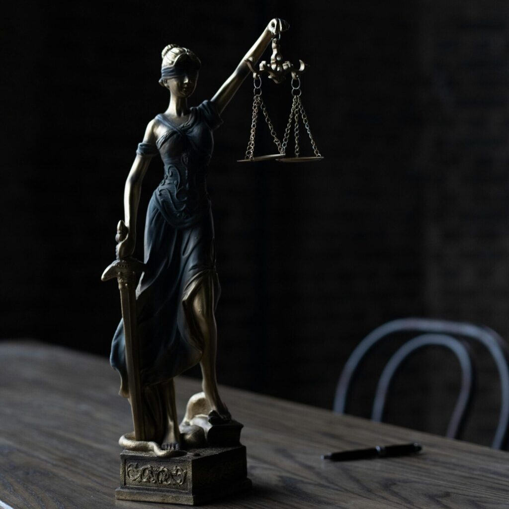 Dramatic lighting on Lady Justice figurine, symbolizing law and fairness.